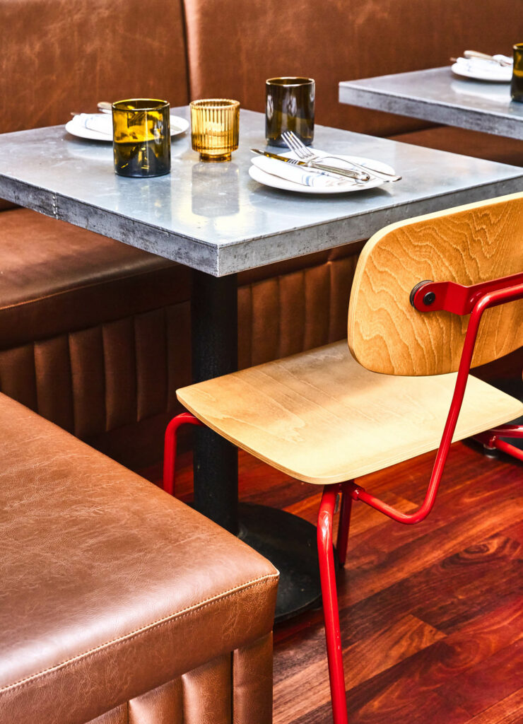 棕色乙烯基长椅环绕着灰色桌子的背面，另一侧是红色和木椅