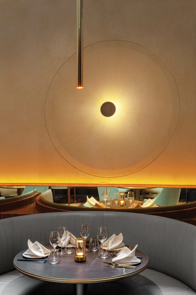 圆形形式主导着餐厅的座位角落，桌子、长椅和壁灯都是定制的，触感超细纤维覆盖在墙上。